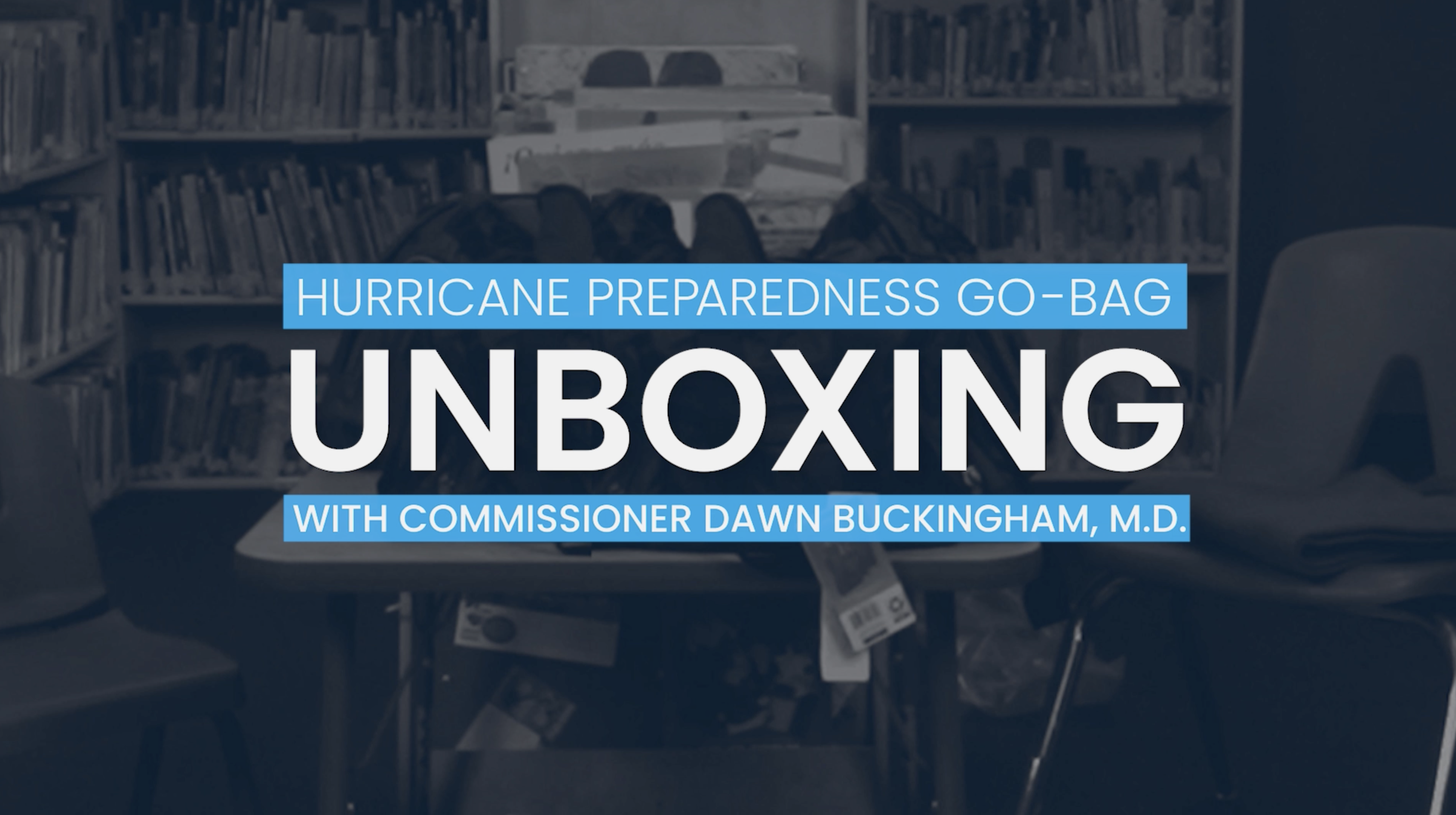 An empty classroom with books and desks with the title "Hurricane Preparedness Go-Bag Unboxing with Commissioner Dawn Buckingham, M.D.