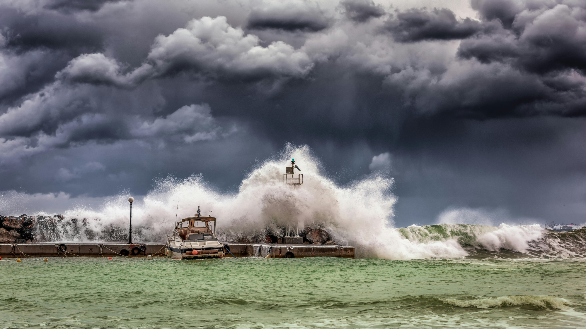 Storm waves crash on tied up boats with storm clouds.