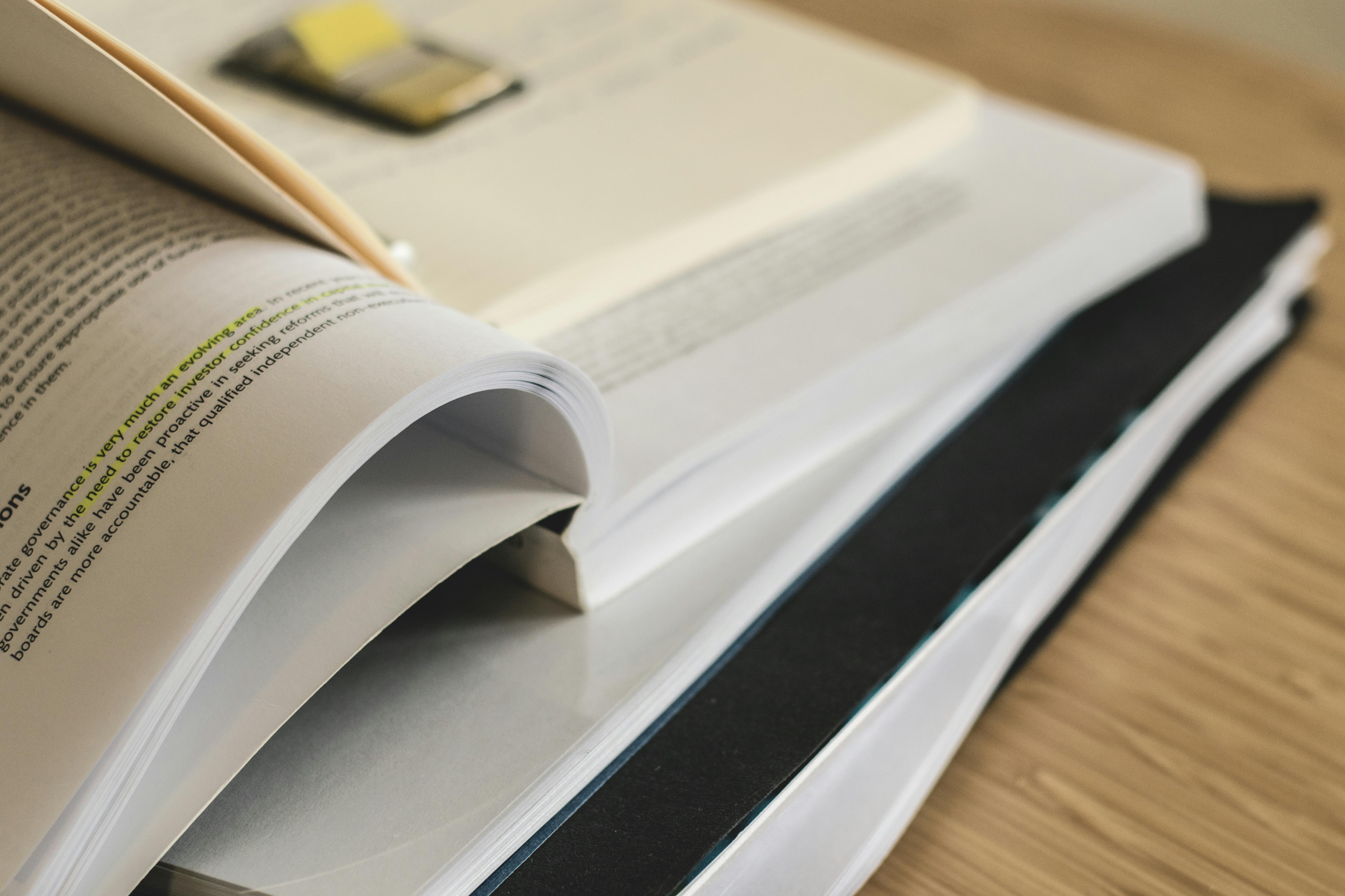 Close up of a stack of open books and notes on a desk.