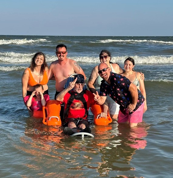 A gentleman enjoys the water at Jamaica Beach with the help of a Mobility Chair