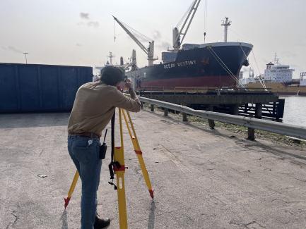 A surveyor uses survey equipment near a gulf port.