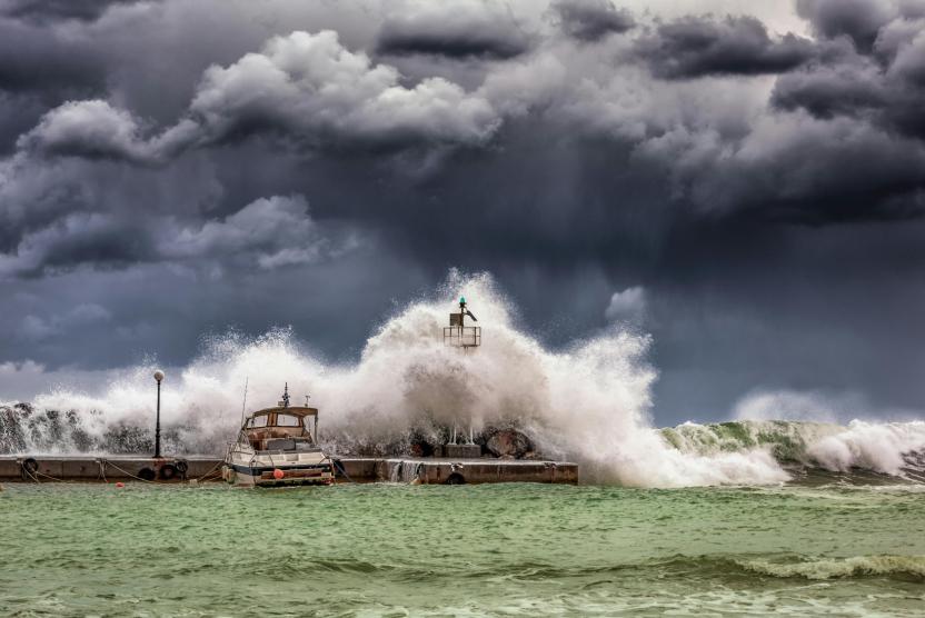 Storm waves crash on tied up boats with storm clouds.
