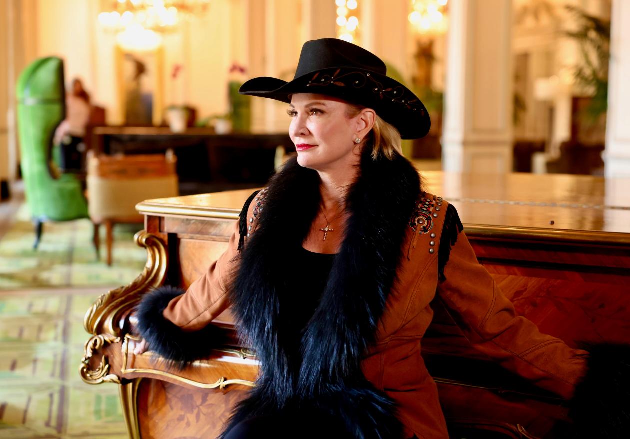 Commissioner Dawn Buckingham, M.D. sitting at a piano wearing a cowboy hat and fur-fringed coat